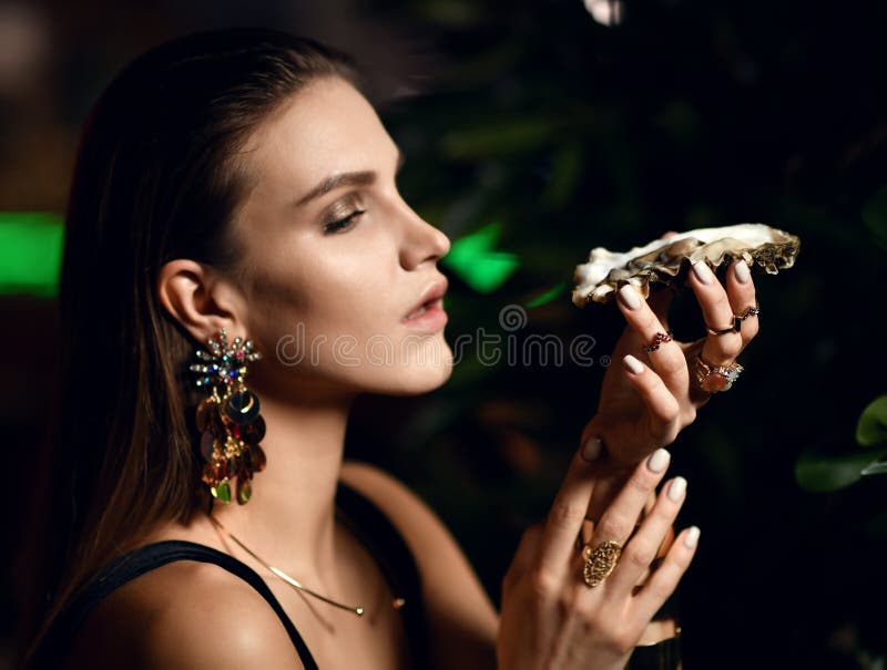 La donna castana di bello modo sexy in ristorante interno costoso mangia le ostriche fotografia stock La donna castana di bello modo sexy in ristorante interno costoso mangia le ostriche fotografia stock