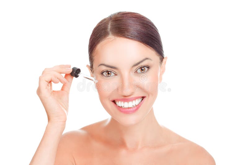 La donna che applica le anti grinze mimiche osserva sorridere dell'olio essenziale del siero del fronte fotografia stock libera da diritti La donna che applica le anti grinze mimiche osserva sorridere dell'olio essenziale del siero del fronte fotografia stock libera da diritti