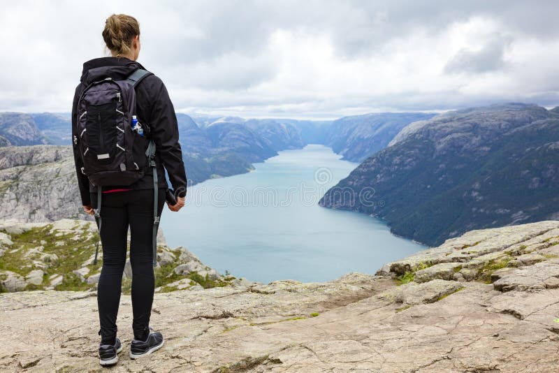 La donna che fa un'escursione alla roccia del quadro di comando dentro lysefjorden la Norvegia fotografie stock La donna che fa un'escursione alla roccia del quadro di comando dentro lysefjorden la Norvegia fotografie stock