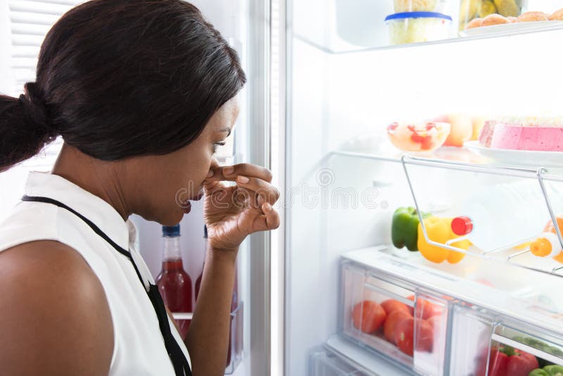 La donna che tiene il suo naso vicino sporca l'alimento in frigorifero