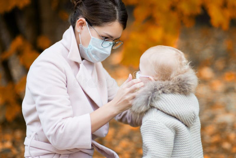 La Mamma Con Una Maschera in Viso Tiene in Braccio Una Bambina. Donna E  Bambino in Maschere Mediche Immagine Stock - Immagine di madre, infezione:  160787281