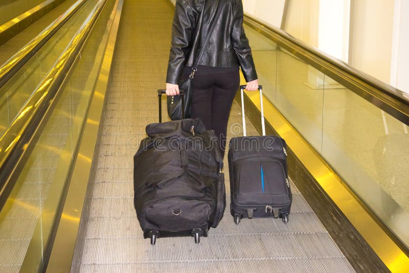 La donna con valigie che cammina alla scala mobile all'aeroporto immagine stock La donna con valigie che cammina alla scala mobile all'aeroporto immagine stock
