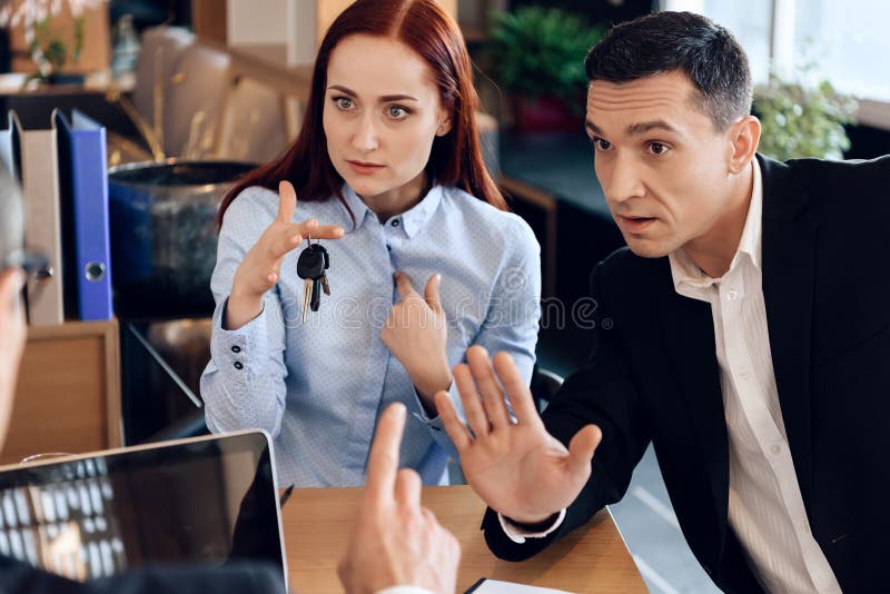 La donna dai capelli rossi sta tenendo sulle chiavi del dito che si siedono accanto all'uomo adulto nell'ufficio del ` s dell'avv immagine stock La donna dai capelli rossi sta tenendo sulle chiavi del dito che si siedono accanto all'uomo adulto nell'ufficio del ` s dell'avv immagine stock