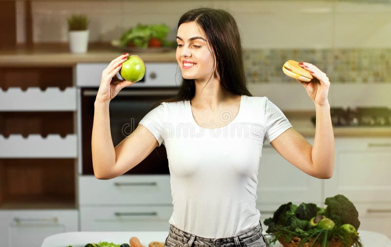 La donna decide fra Apple e l'hamburger fotografia stock La donna decide fra Apple e l'hamburger fotografia stock