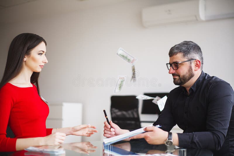 La donna di affari dà i soldi agli uomini La donna vestita in vestito rosso dà il dono Uomo di affari in Gray Jacket Gets Bribe a immagini stock libere da diritti La donna di affari dà i soldi agli uomini La donna vestita in vestito rosso dà il dono Uomo di affari in Gray Jacket Gets Bribe a immagini stock libere da diritti
