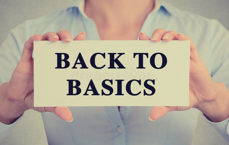 Closeup businesswoman hands holding white card sign note with back to basics text message isolated on grey wall office background. Retro instagram style image. Closeup businesswoman hands holding white card sign note with back to basics text message isolated on grey wall office background. Retro instagram style image