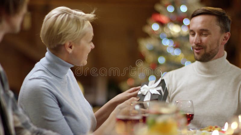La donna dà un regalo per equipaggiare dalla tavola della famiglia di Natale