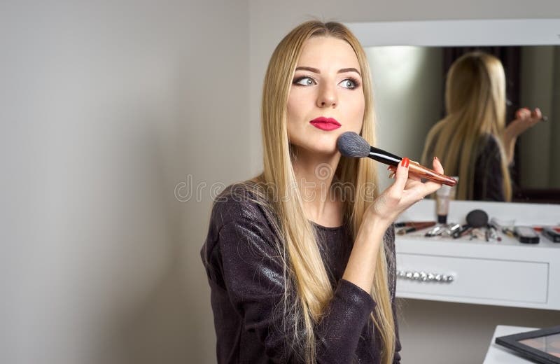 La donna fa il trucco prima di uno specchio fotografia stock La donna fa il trucco prima di uno specchio fotografia stock