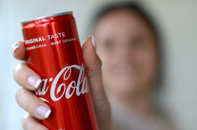 La donna felice che tiene latta di alluminio analcolica di Coca-Cola barattolo nell'interno del garage immagine stock libera da diritti La donna felice che tiene latta di alluminio analcolica di Coca-Cola barattolo nell'interno del garage immagine stock libera da diritti