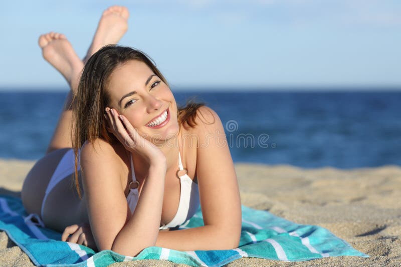 La donna felice con bianco perfeziona il sorriso che riposa sulla spiaggia immagine stock