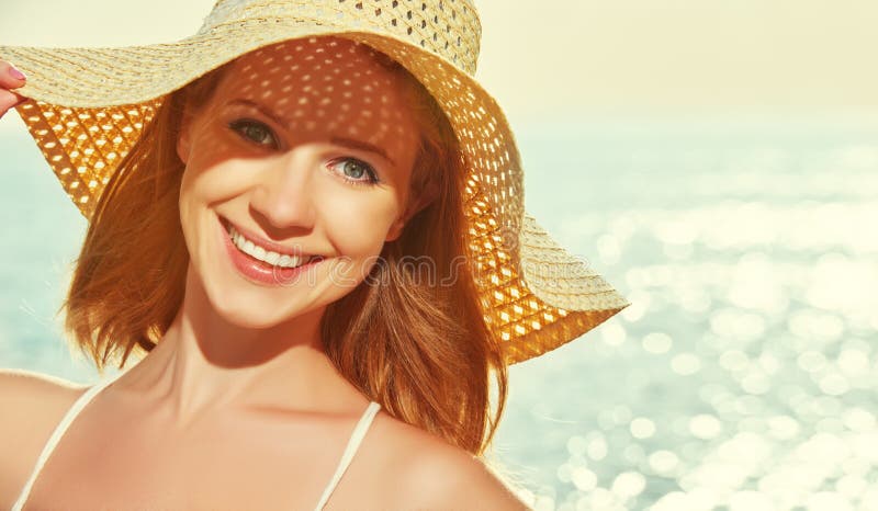La donna felice di bellezza in cappello gode del mare al tramonto sulla spiaggia