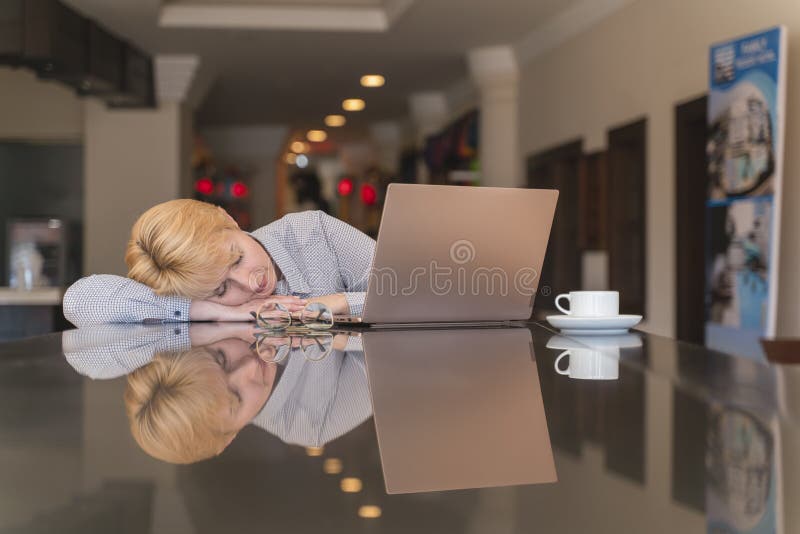 La donna in menopausa al lavoro si sente male, depressione della forza e riposo Dorme sul posto di lavoro prima del portatile al fotografia stock La donna in menopausa al lavoro si sente male, depressione della forza e riposo Dorme sul posto di lavoro prima del portatile al fotografia stock