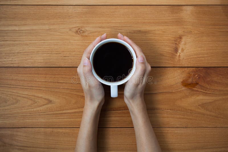 La donna passa a tazza della tenuta della bevanda calda quella condizione sulla linguetta di legno fotografia stock libera da diritti La donna passa a tazza della tenuta della bevanda calda quella condizione sulla linguetta di legno fotografia stock libera da diritti