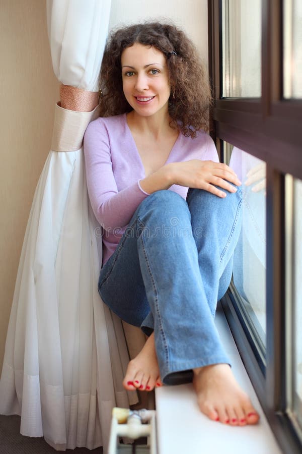 La Donna A Piedi Nudi Si Siede Sul Windowsill Ed Osserva Fotografia