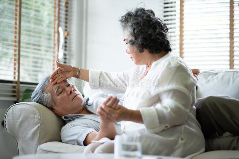 La donna senior asiatica sta prendendo si preoccupa il suo marito alla loro casa fotografia stock libera da diritti La donna senior asiatica sta prendendo si preoccupa il suo marito alla loro casa fotografia stock libera da diritti