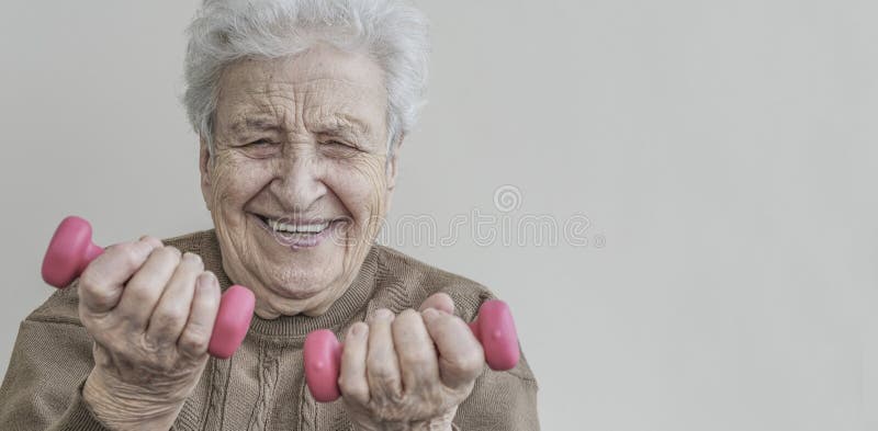 La donna senior felice sta sollevando difficile le teste di legno immagini stock La donna senior felice sta sollevando difficile le teste di legno immagini stock