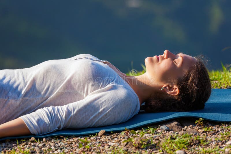 La donna si rilassa in asana Savasana di yoga all'aperto fotografia stock libera da diritti La donna si rilassa in asana Savasana di yoga all'aperto fotografia stock libera da diritti
