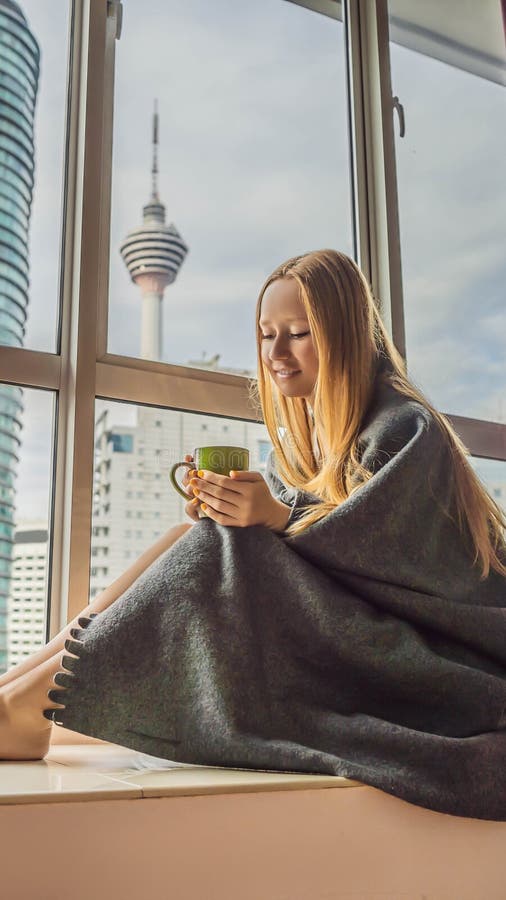 La donna si è avvolta in una coperta e nell'esame del FORMATO VERTICALE grande della città per la storia di Instagram o la dimens immagini stock La donna si è avvolta in una coperta e nell'esame del FORMATO VERTICALE grande della città per la storia di Instagram o la dimens immagini stock