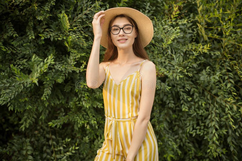 La donna soddisfatta in una tuta ed in un cappello gialli sta stando nella città sulla via fotografie stock libere da diritti La donna soddisfatta in una tuta ed in un cappello gialli sta stando nella città sulla via fotografie stock libere da diritti