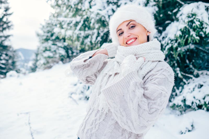 La donna sorridente in cappello tricottante accogliente di pelliccia e del pullover resta il wint del OM immagini stock La donna sorridente in cappello tricottante accogliente di pelliccia e del pullover resta il wint del OM immagini stock