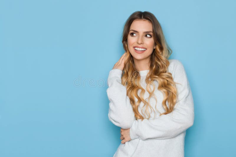 La donna sorridente in maglione pastello blu sta distogliendo lo sguardo fotografie stock La donna sorridente in maglione pastello blu sta distogliendo lo sguardo fotografie stock