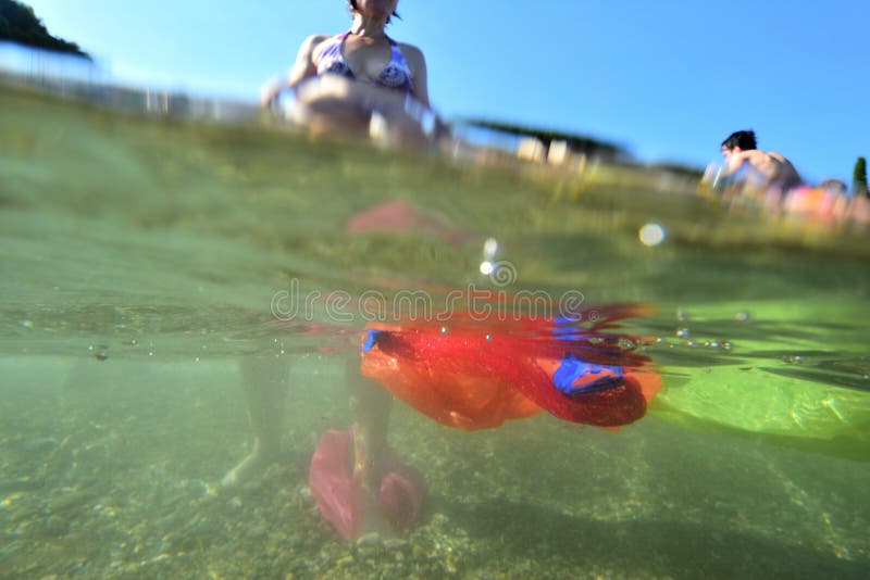 La donna sulla spiaggia che entra nell'acqua e nel mare è piena di immondizia di plastica fotografie stock libere da diritti La donna sulla spiaggia che entra nell'acqua e nel mare è piena di immondizia di plastica fotografie stock libere da diritti