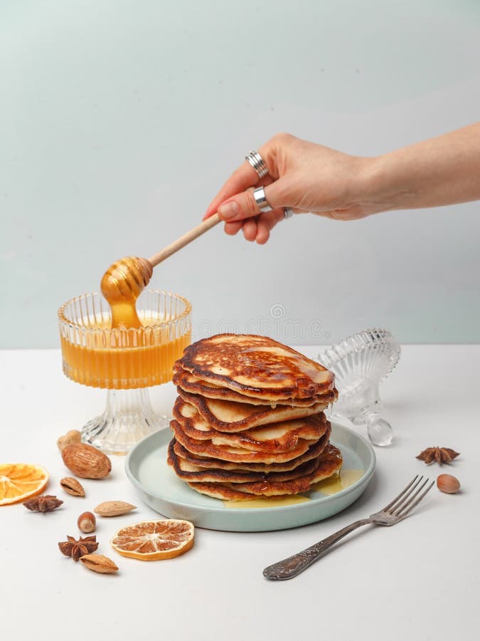 La donna versa il miele sui pancake Il concetto di una prima colazione deliziosa fotografia stock libera da diritti La donna versa il miele sui pancake Il concetto di una prima colazione deliziosa fotografia stock libera da diritti