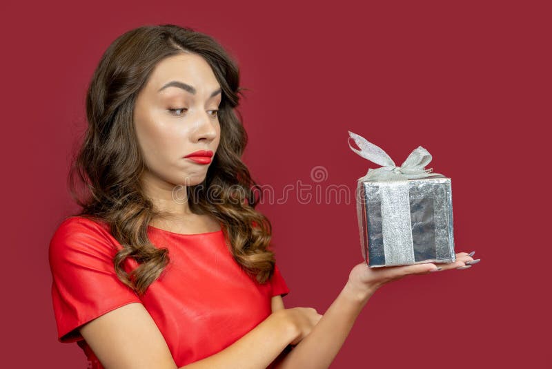 La donna è delusa dal regalo su un sfondo rosso immagine stock libera da diritti