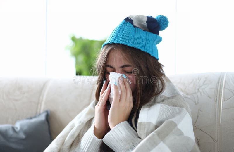 Woman stayed home on sick leave sitting on couch wipes snot with runny napkin portrait. Season disease concept. Woman stayed home on sick leave sitting on couch wipes snot with runny napkin portrait. Season disease concept