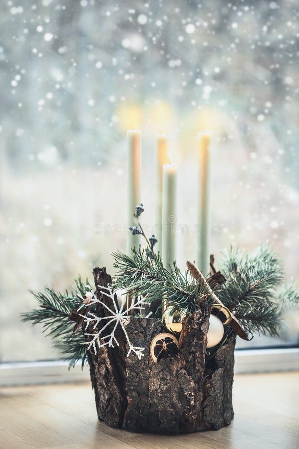 La décoration chaleureuse de la maison de Noël avec quatre bougies en feu, des branches de cèdre et des flocons de neige se tient photographie stock libre de droits