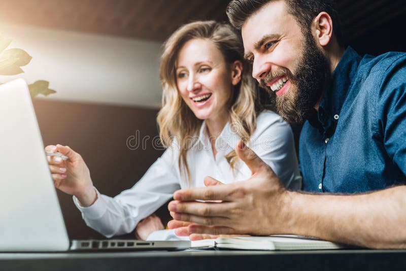 La empresaria y el hombre de negocios se están sentando en el escritorio contra el ordenador portátil y están discutiendo el proy imágenes de archivo libres de regalías La empresaria y el hombre de negocios se están sentando en el escritorio contra el ordenador portátil y están discutiendo el proy imágenes de archivo libres de regalías