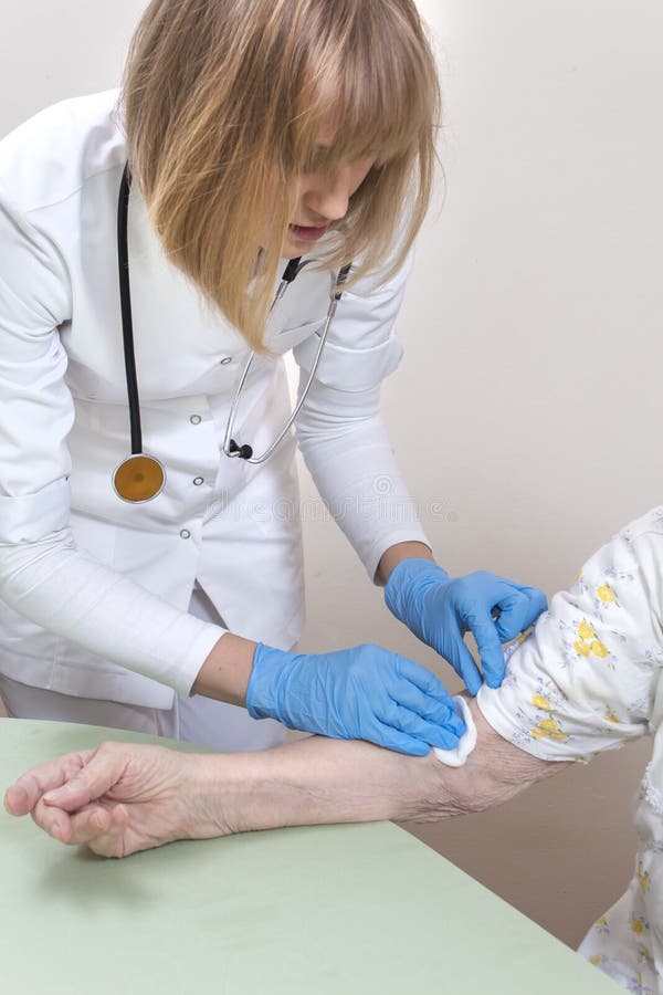 La enfermera en guantes disponibles desinfecta el lugar en las manos de una mujer mayor antes de tomar sangre fotos de archivo libres de regalías La enfermera en guantes disponibles desinfecta el lugar en las manos de una mujer mayor antes de tomar sangre fotos de archivo libres de regalías