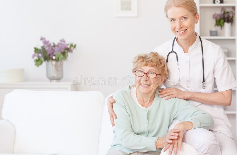 La enfermera sonriente se sienta con una más vieja mujer imagen de archivo La enfermera sonriente se sienta con una más vieja mujer imagen de archivo