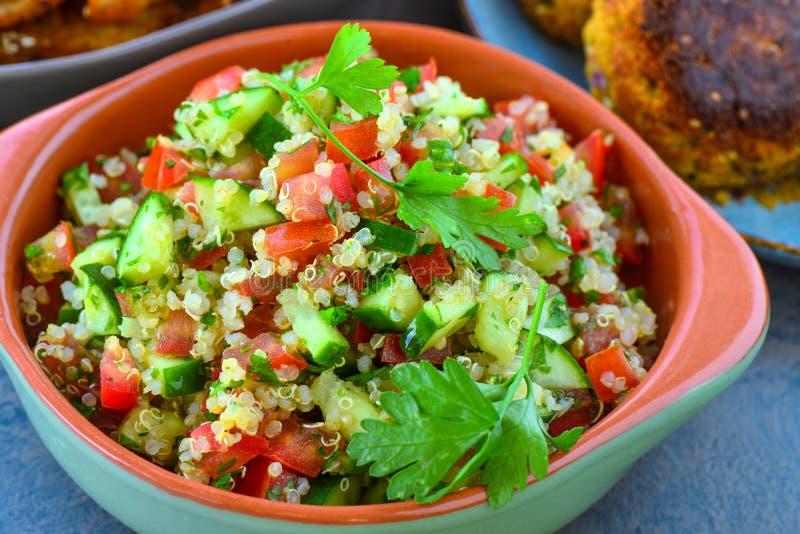 Vegan quinoa salad served in earthen bowl with fresh cucumber,tomato,onions,mint and parsely. Vegan quinoa salad served in earthen bowl with fresh cucumber,tomato,onions,mint and parsely