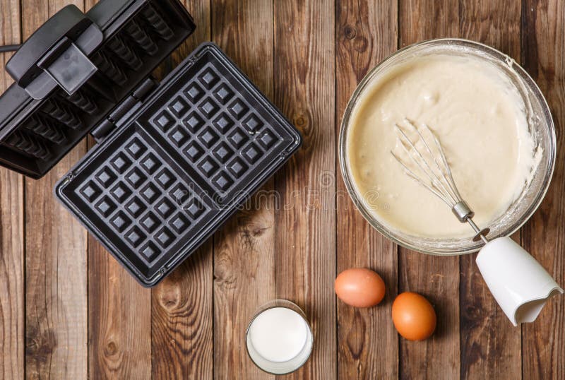 La fabricación se enrolla en casa - el hierro de galleta, estropea en cuenco e ingredientes - leche y los huevos foto de archivo libre de regalías La fabricación se enrolla en casa - el hierro de galleta, estropea en cuenco e ingredientes - leche y los huevos foto de archivo libre de regalías