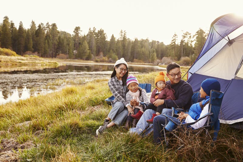 La famiglia asiatica su un viaggio di campeggio si rilassa fuori della loro tenda