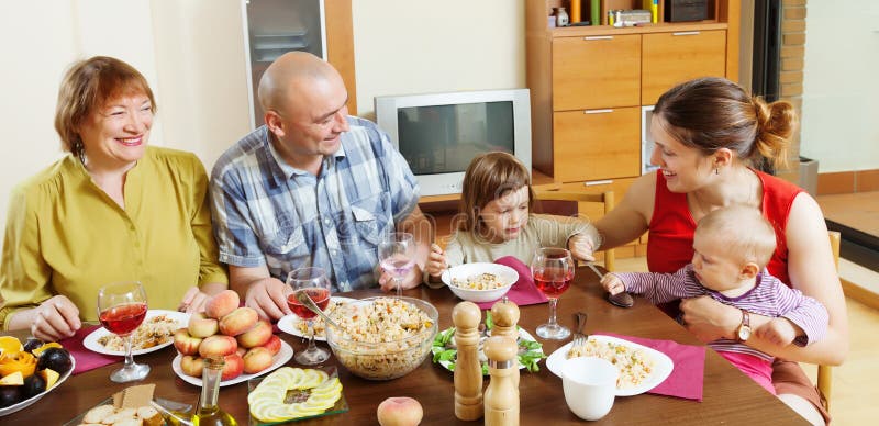 La famiglia di diverse generazioni felice comunica sopra la tavola immagini stock La famiglia di diverse generazioni felice comunica sopra la tavola immagini stock