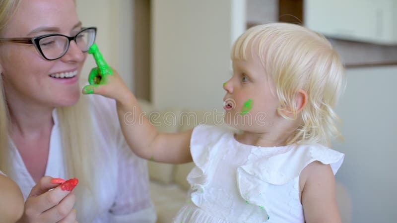 La famiglia felice dipinge i colori La madre e la figlia divertendosi e si dipingono ` s sui fronti a casa Scherzi della famiglia video d archivio La famiglia felice dipinge i colori La madre e la figlia divertendosi e si dipingono ` s sui fronti a casa Scherzi della famiglia video d archivio