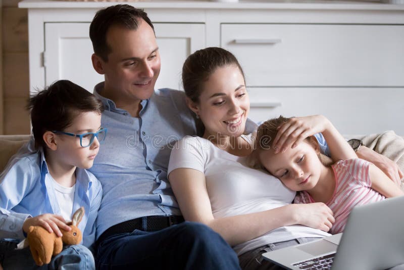 La famiglia felice si rilassa nei fumetti di sorveglianza del salone sul computer portatile