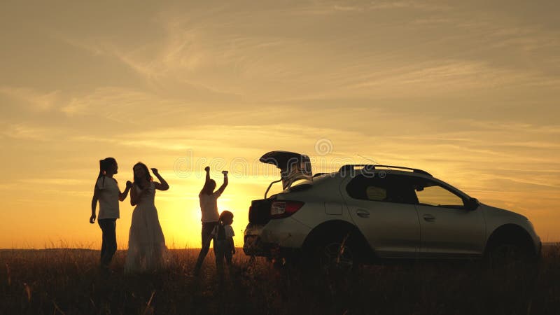 La famiglia felice viaggia in macchina. mamma e bambini fermati in macchina per riposarsi. madre e figlie ballano e ammirano la stock footage