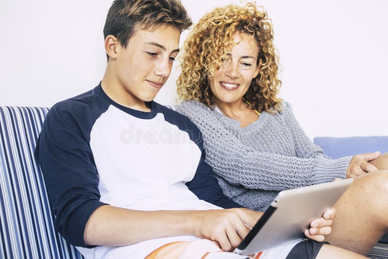 La familia alegre y feliz en casa que estudiaba en Internet de la tableta conect? imagen brillante de la madre y del hijo cauc?si imagen de archivo libre de regalías La familia alegre y feliz en casa que estudiaba en Internet de la tableta conect? imagen brillante de la madre y del hijo cauc?si imagen de archivo libre de regalías