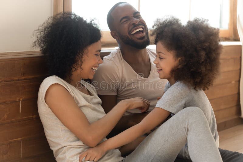 La familia birracial feliz con un niño se divierte en casa