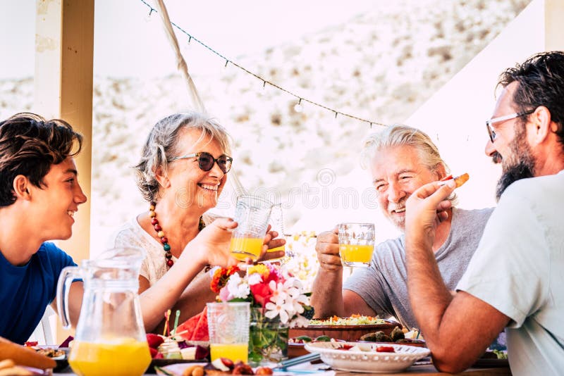 La familia caucásica, de edades mixtas alegres y alegres, se queda a comer en casa o en el restaurante que la gente disfruta fotos de archivo libres de regalías