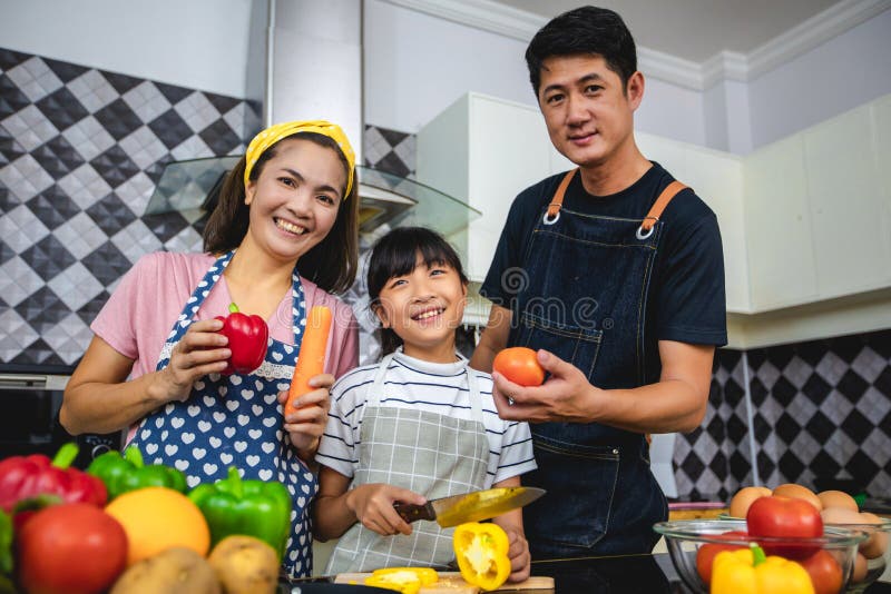 La familia feliz tiene el pap?, la mam? y su peque?a hija cocinando junta en la cocina imagen de archivo libre de regalías La familia feliz tiene el pap?, la mam? y su peque?a hija cocinando junta en la cocina imagen de archivo libre de regalías
