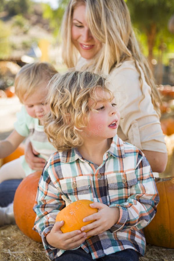 La familia joven disfruta de un día en el remiendo de la calabaza imágenes de archivo libres de regalías La familia joven disfruta de un día en el remiendo de la calabaza imágenes de archivo libres de regalías