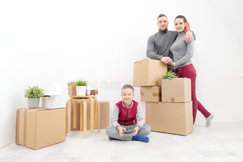 La familia, la mujer del hombre y el hijo jovenes del niño se sienta en el piso en nuevos apartamentos Cajas con el cargo en un f fotos de archivo libres de regalías La familia, la mujer del hombre y el hijo jovenes del niño se sienta en el piso en nuevos apartamentos Cajas con el cargo en un f fotos de archivo libres de regalías