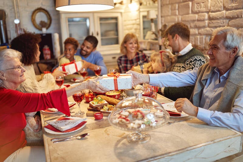 La familia y los amigos gozan en los regalos de la cena y del intercambio de la Navidad juntos fotografía de archivo La familia y los amigos gozan en los regalos de la cena y del intercambio de la Navidad juntos fotografía de archivo