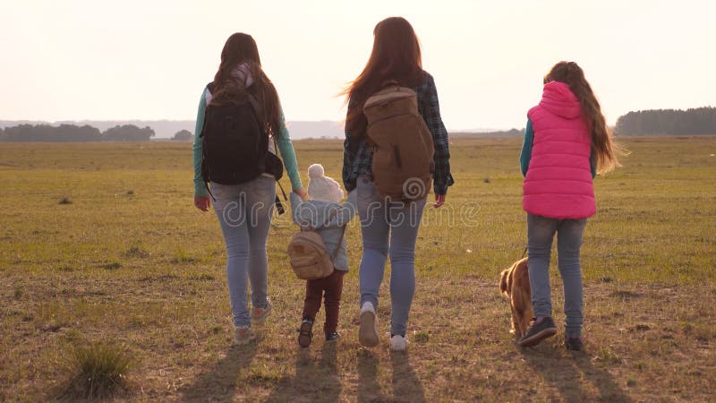 Family with backpacks travels with a dog. teamwork of a close-knit family. mother, daughters and home pets tourists. The concept of a sports family holiday in nature. Family with backpacks travels with a dog. teamwork of a close-knit family. mother, daughters and home pets tourists. The concept of a sports family holiday in nature.