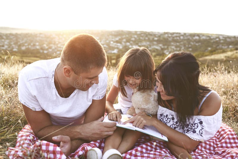 La famille lit un livre en nature photographie stock libre de droits La famille lit un livre en nature photographie stock libre de droits