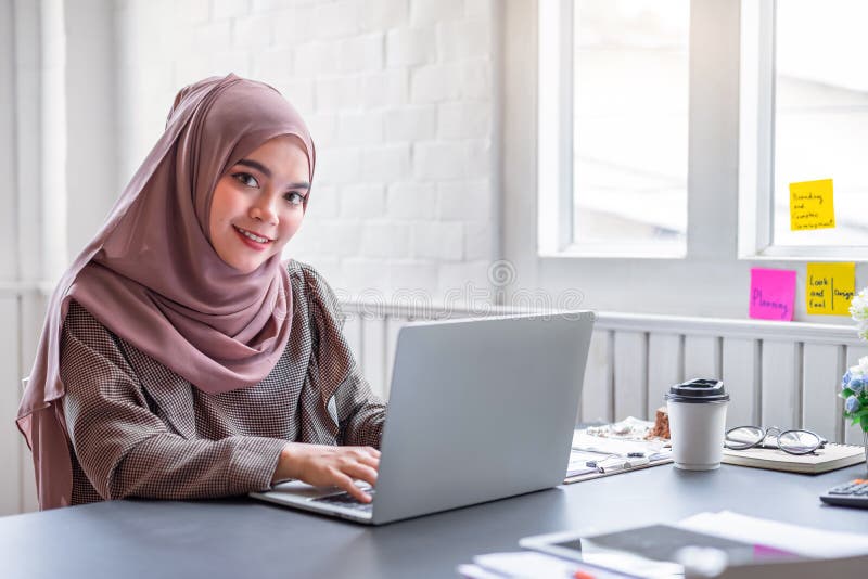La felice e bella imprenditrice musulmana marrone hijab che lavora per la finanza con il business report e la calcolatrice nel pr fotografie stock libere da diritti La felice e bella imprenditrice musulmana marrone hijab che lavora per la finanza con il business report e la calcolatrice nel pr fotografie stock libere da diritti